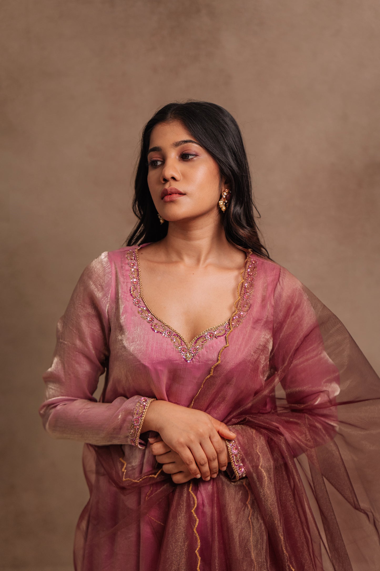Model Jaina Parmar posing for closeup detailing in a hand embroidered tissue chiffon anarkali in onion pink (dual tone), paired with an embroidered tulle dupatta in wine red by team AKloset.