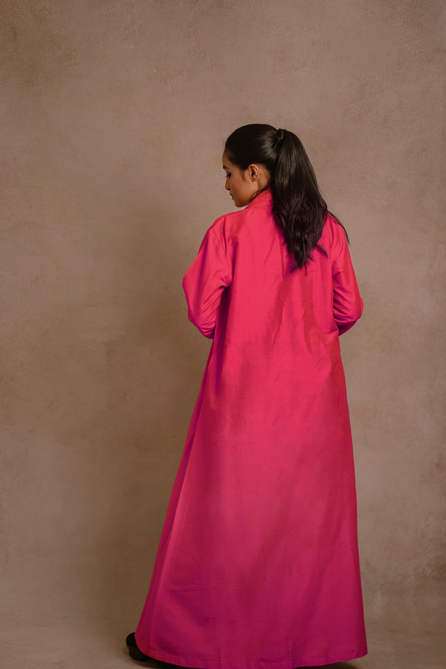 Model Krisha showcasing back design in a long jacket in hot pink paired with a crop top & bell bottom pant in yellow by team AKloset.
