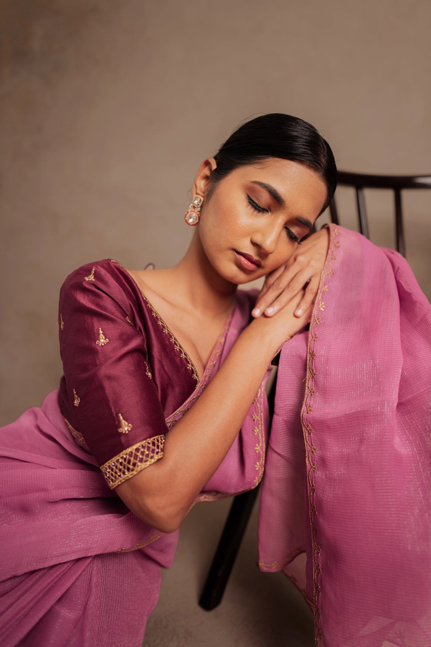 Model Premika Sekar in a seated pose during photoshoot in an embroidered Tissue Chiffon Saree in Onion Pink with an Embroidered Chanderi Blouse in Plum.