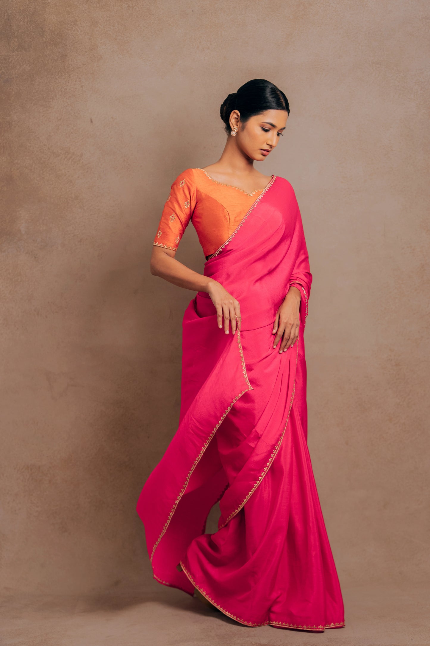 Model Premika Sekar posing during photoshoot in a pink shimmer chiffon saree paired with an embroidered orange raw silk blouse designed by team AKloset.
