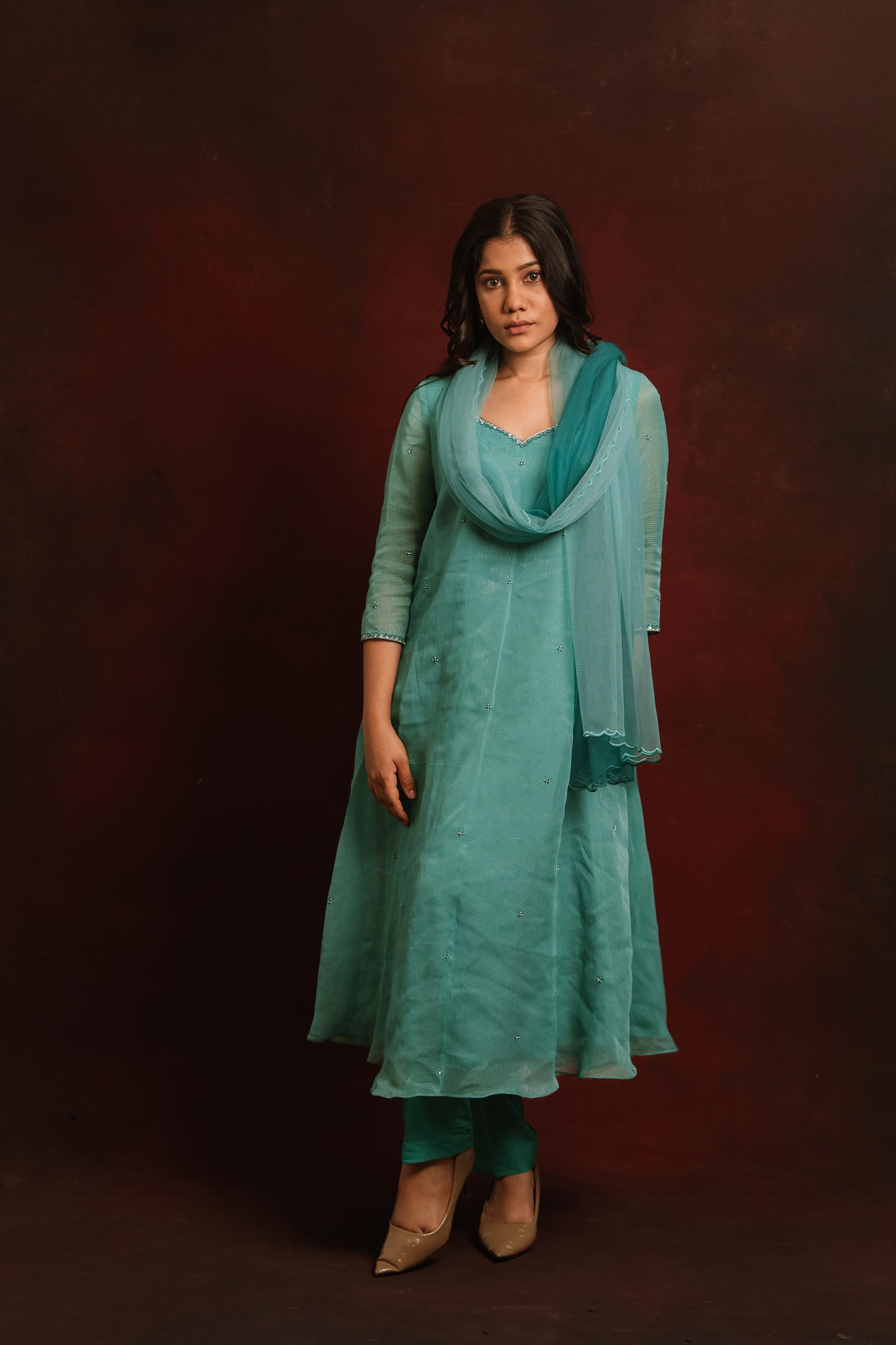 Model posing with dupatta in a teal blue tissue chiffon salwar set by AKloset.