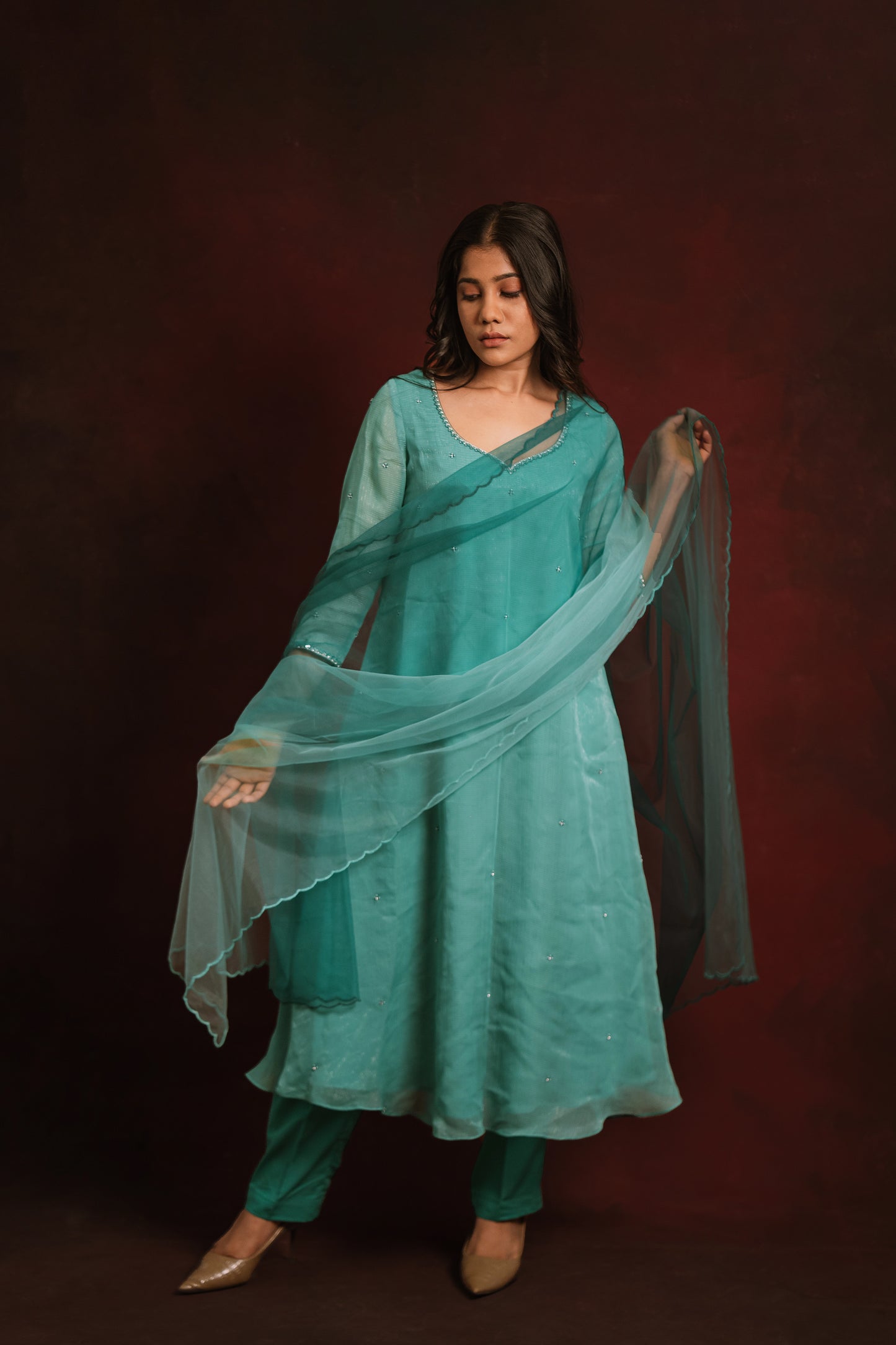 Model posing with net dupatta in a teal blue tissue chiffon salwar set by AKloset.